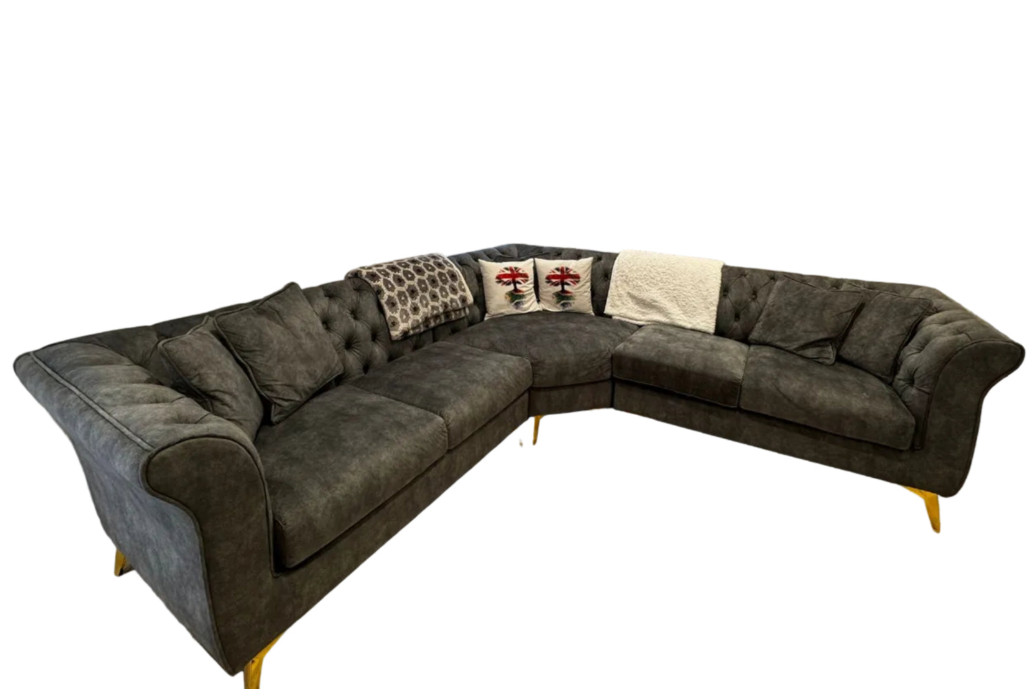 Grey velvet corner sofa with gold legs in a living room.